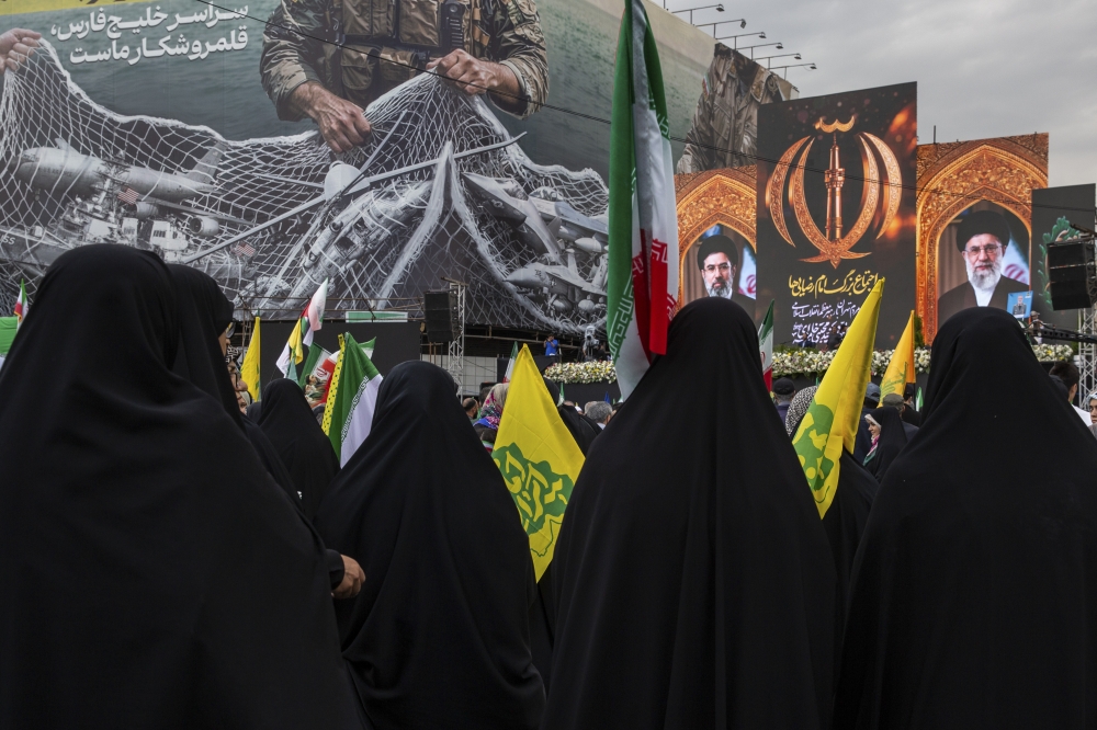 People gather in front of a billboard during a rally in support of the new supreme leader in Enghelab Square in Tehran. — NYT file photo
