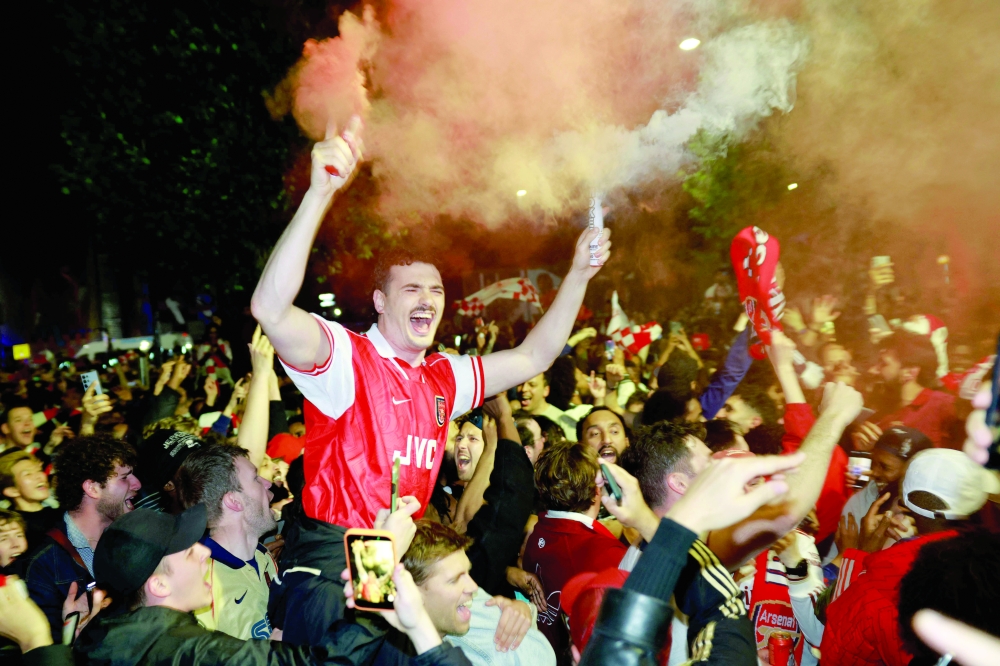 Arsenal fans celebrate their team winning the English Premier League, outside the Emirates Stadium in London on May 19, 2026.  Arsenal celebrated their first Premier League title for 22 years late on May 19 after Manchester City were held to a 1-1 draw by Bournemouth, sparking wild scenes of joy around the Emirates Stadium.  (Photo by Brook Mitchell / AFP)