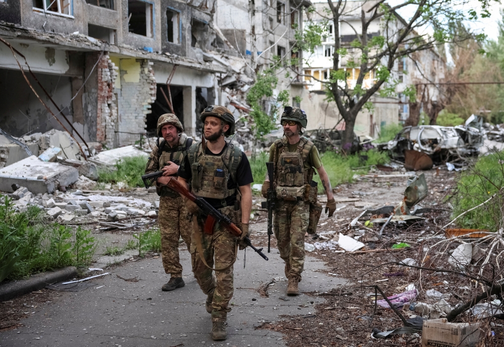 Servicemen of the anti-aircraft missile division of the 15th 'Kara-Dag' Brigade of the Operational Assignment of the National Guard of Ukraine walk near destroyed apartment buildings in the frontline city of Bilozerske in the Donetsk region. - Reuters