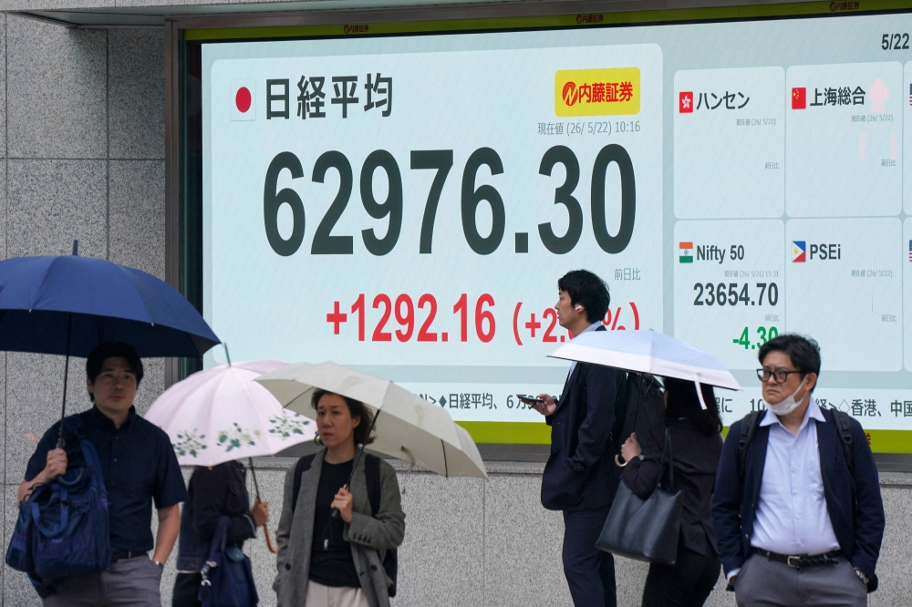 Pedestrians are pictured in front of an electronic quotation boards displaying the Nikkei Stock Average on the Tokyo Stock Exchange along a street in Tokyo on May 22, 2026.  (Photo by Kazuhiro NOGI / AFP)