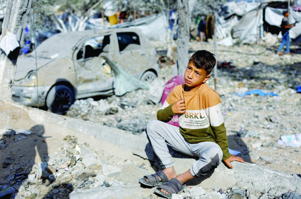 A Palestinian boy sits amidst debris at the site of an Israeli strike in Deir Al Balah, Gaza. — Reuters