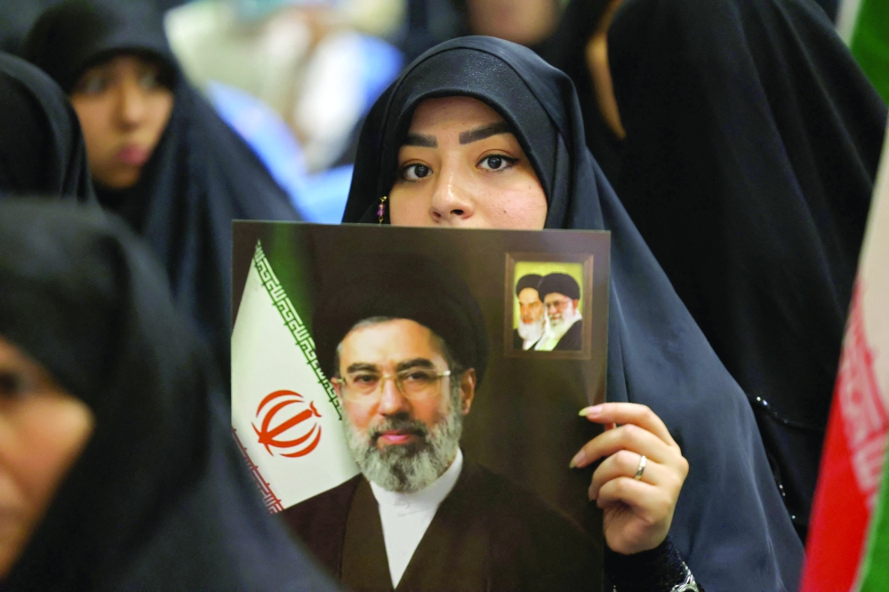 
An Iranian woman holds an image of Iran’s supreme leader Mojtaba Khamenei, as she and others gather in Tehran to commemorate those killed in wars, on Sunday. — AFP 