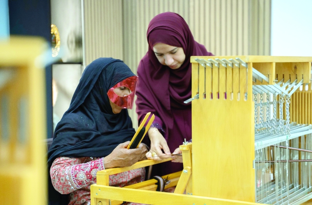 Samira al Futaisi demonstrating weaving techniques to trainees in a hands-on workshop setting.