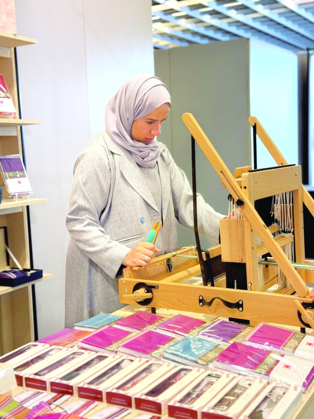 Close-up of Samira al Futaisi’s hands working on a loom, showing the rhythm and skill behind each woven piece.