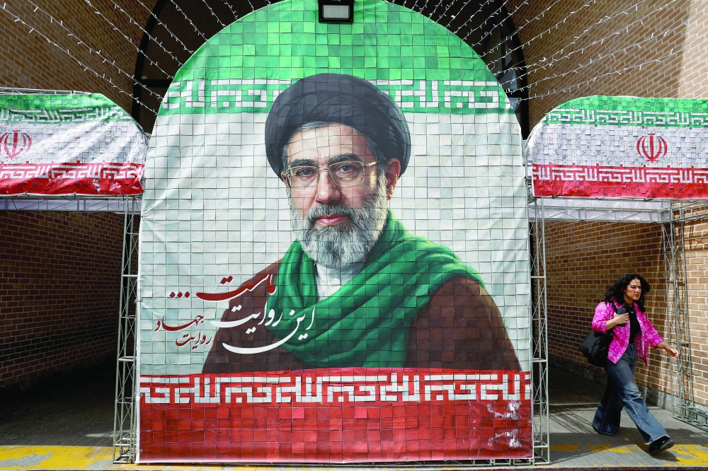 A woman walks next to a banner with a picture of Iran's new Supreme Leader Mojtaba Khamenei in Tehran. — Reuters
