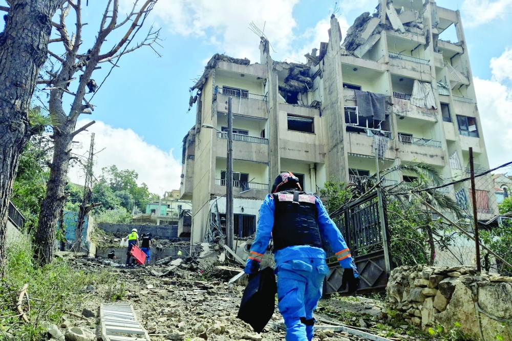 Lebanese rescue workers walk towards the site of an Israeli air raid on the town of Nabatieh. — AFP