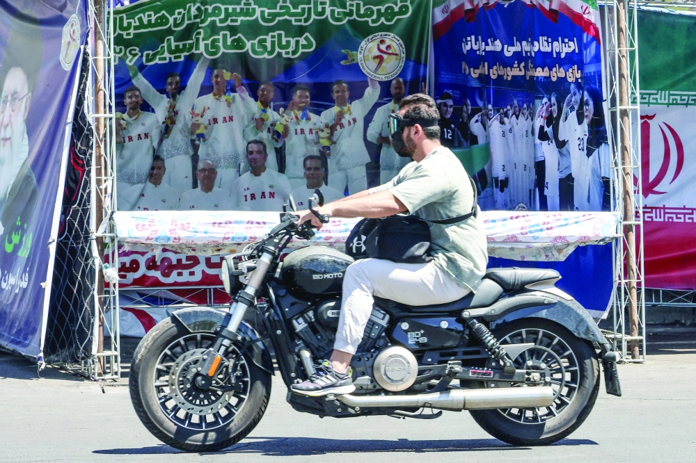 A man rides his motorbike past a banner depicting Iran’s national football team in the upcoming 2026 World Cup, in Tehran. — AFP