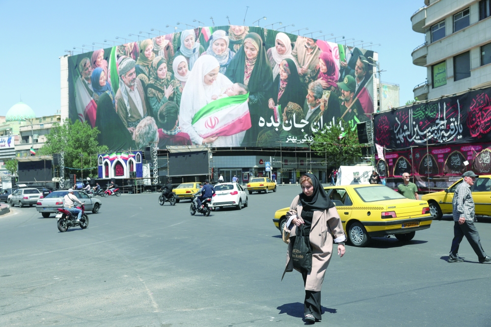 People walk past a billboard with a picture of Iranian people, in Tehran. — Reuters