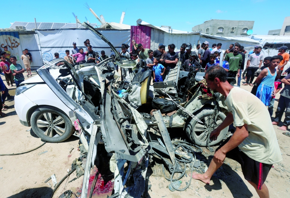 Palestinians inspect the site of an Israeli strike on a vehicle in Khan Younis, in the southern Gaza Strip, May 26, 2026.