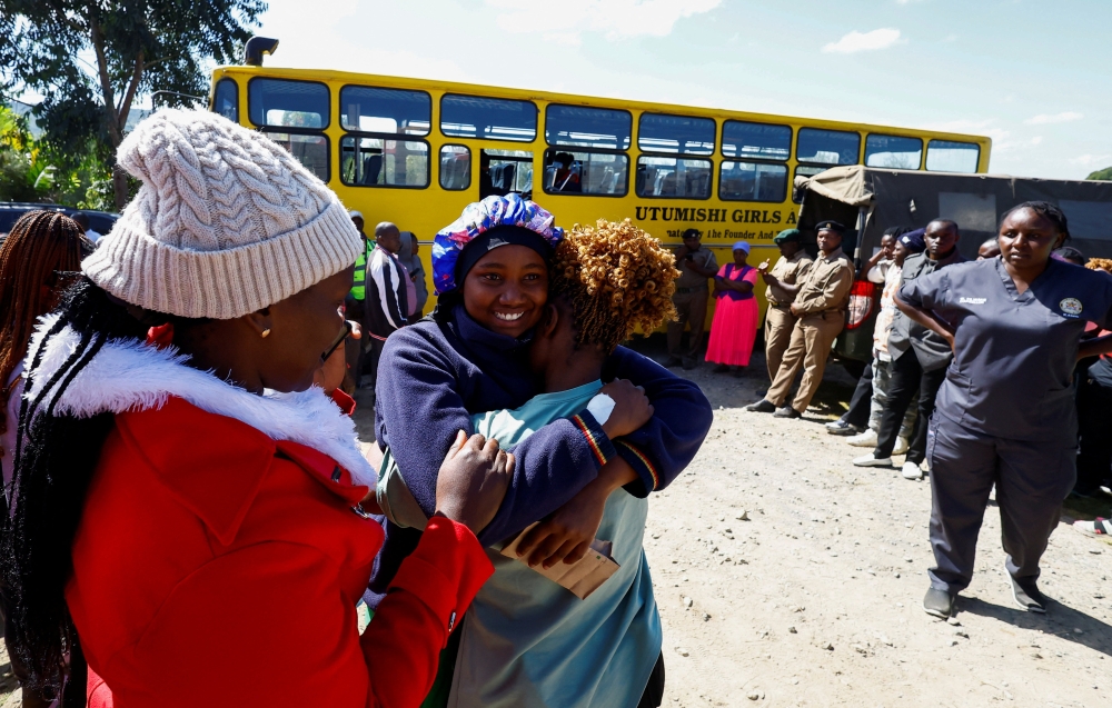 A student injured during a stampede embraces her mother at the Utumishi Girls' Academy Senior School 