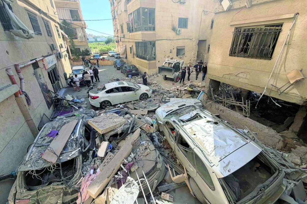 Rescue workers and residents inspect the damage to a building following an Israeli air strike in the Choueifat area, south of Beirut, on the outskirts of the capital’s southern suburbs. - AFP