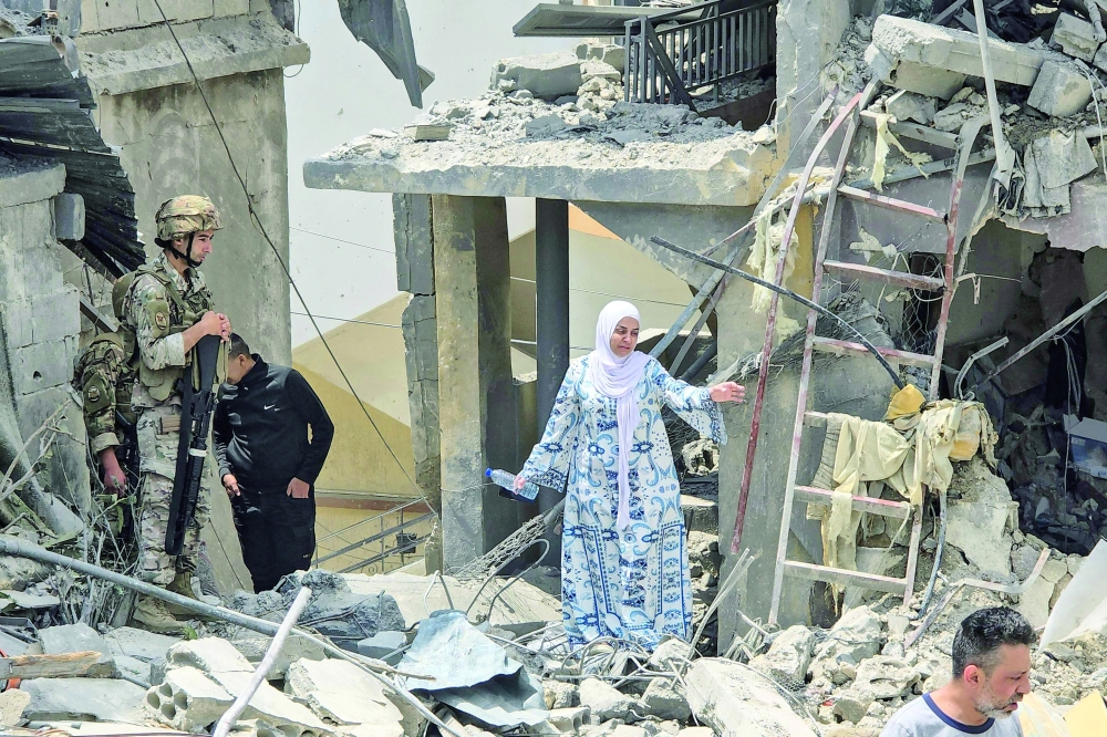 A woman makes her way through the rubble at the site of a residential building hit by an Israeli strike, in Burj al-Shamali. — AFP