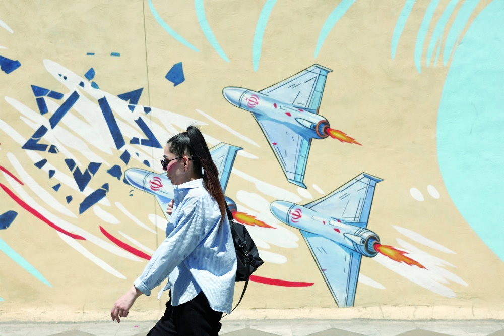 An Iranian woman walks next to an anti-Israeli mural on a street in Tehran, Iran, on Saturday. — Reuters