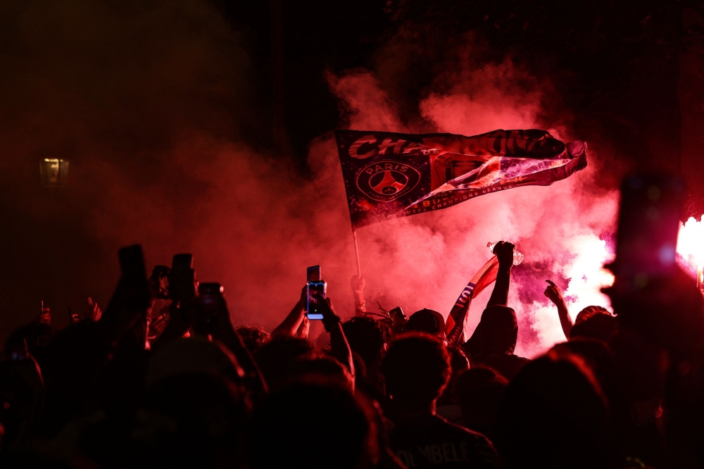 PSG supporters burn flares and wave a flag during gatherings after PSG won the UEFA Champions League final between Paris Saint-Germain (PSG) and Arsenal FC played in Budapest, in Paris on May 30, 2026.