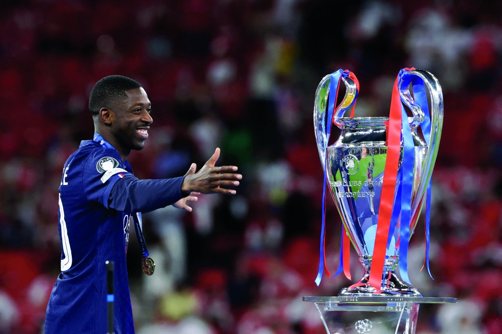 Paris Saint-Germain's French forward #10 Ousmane Dembele looks at the trophy after winning the UEFA Champions League final football match. — AFP