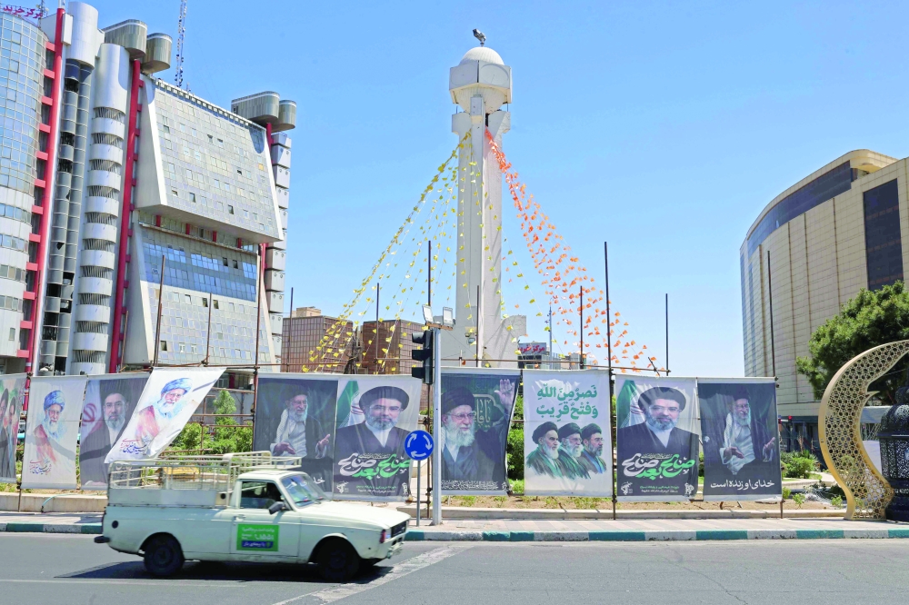 A vehicle drives past installed banners at the Sadeghiyeh Square in Tehran. — AFP
