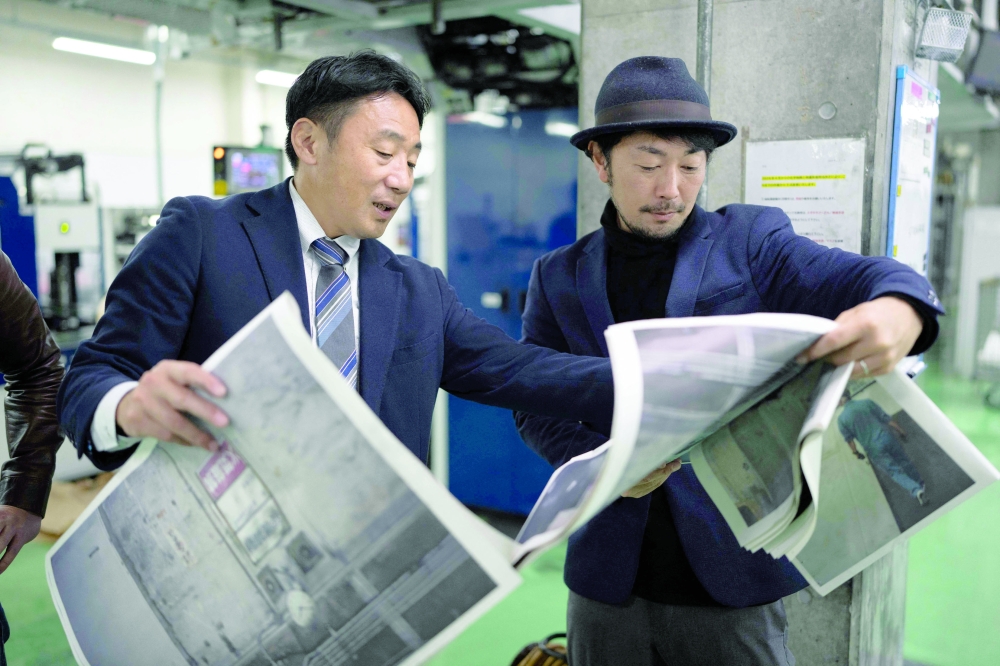 This picture taken on March 19, 2026 shows photographer Kazuma Obara (R) and a staff member inspecting the printing quality of his work titled "The Newspaper” at the Kyoto Shimbun factory in Kumiyama, Kyoto prefecture. Despite the decline of the publishing industry, self-publication and handmade "zine" magazines are growing in popularity in Japan, reflecting the country's enduring love of paper in the digital era. - To go with AFP story Japan-culture-books, FEATURE by Natsuko Fukue and Atish Patel
