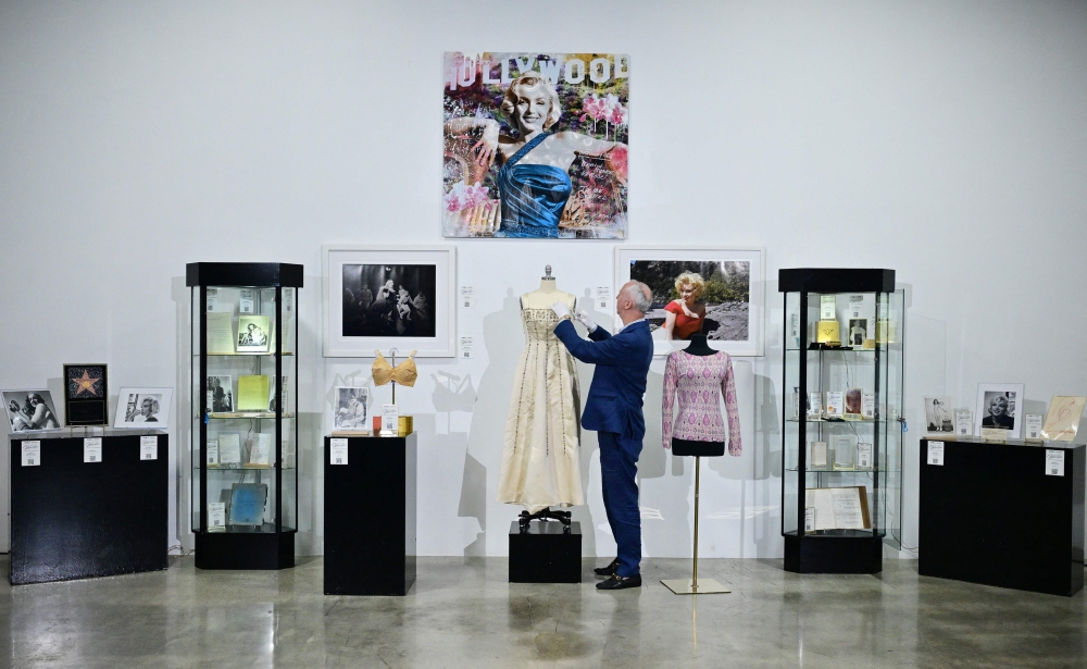 Martin Nolan, Julien's Auctions' executive director and co-founder, adjusts a display of Marilyn Monroe memorabilia, including a 1950s evening gown, during a preview of Julien's Auctions' "100 Years of Marilyn" at Julien's Studios in Gardena, California, on May 27, 2026, ahead of the June 4 auction marking what would have been the Hollywood icon's 100th birthday.  (Photo by Frederic J. BROWN / AFP)
