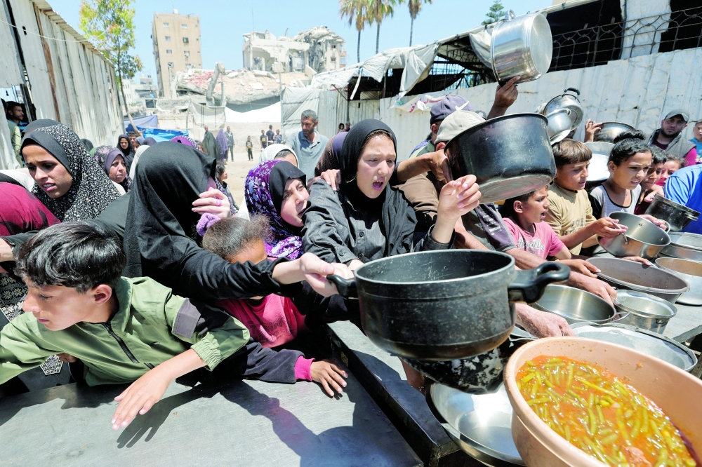 Palestinians gather to receive food from a charity kitchen, in Gaza City. — Reuters