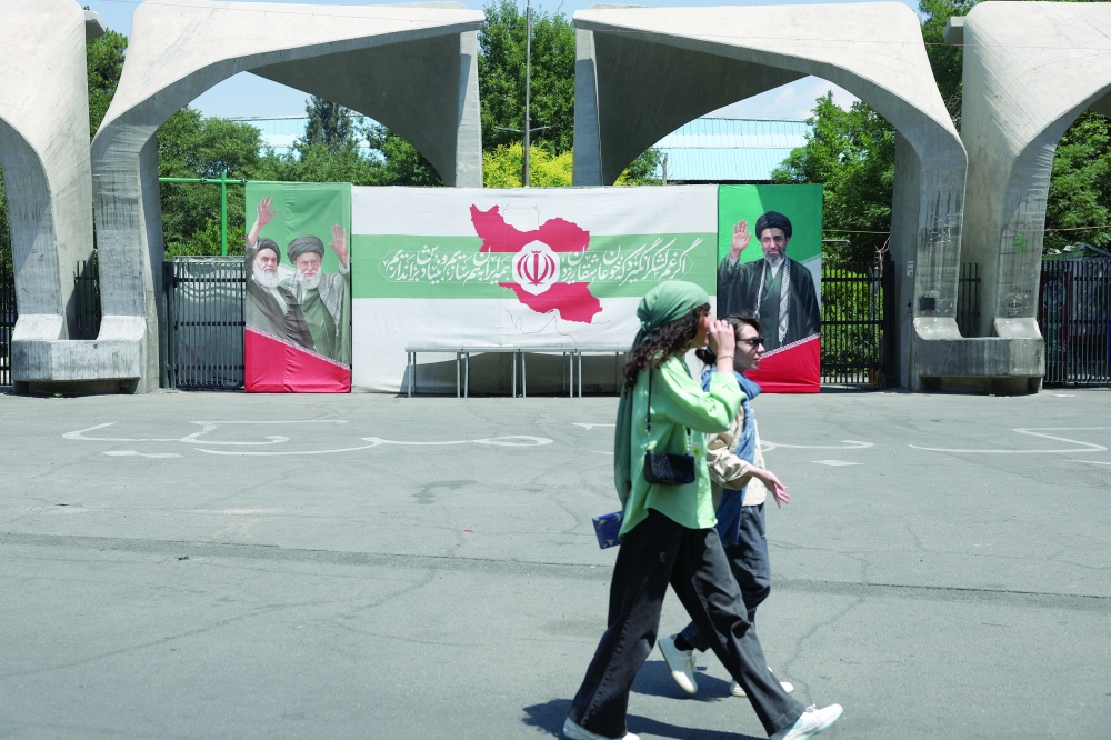 Iranian women walk past a banner with pictures of  the late leader of the Islamic Revolution, Ayatollah Ruhollah Khomeini, the late Iran's Supreme Leader Ayatollah Ali Khamenei, and Iran's Supreme Leader Mojtaba Khamenei, on a street in Tehran, Iran, on Wednesday. - Reuters