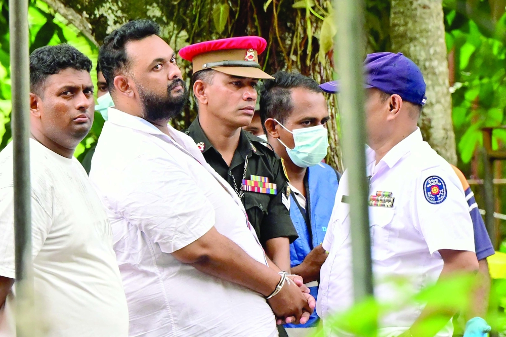 Sri Lankan police personnel escort Isuru Anushka, manager of the Maupiya Sewana Elders Home, to the fire accident site in Batagoda. — AFP