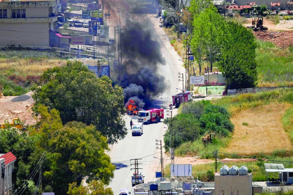 First responders attend to a burning vehicle targeted by an Israeli drone attack in the southern Lebanese city of Nabatieh