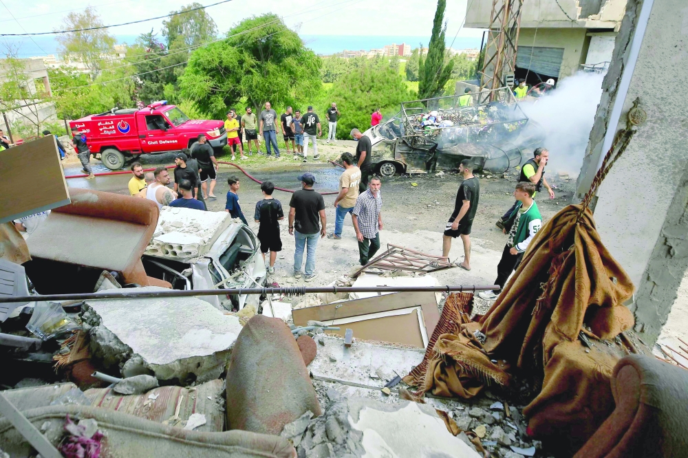 People inspect damage following Israeli bombardment on a building in the village of Saksakiyeh in southern Lebanon. — AFP