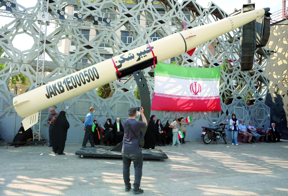 Iranians stand next to a symbol of a Kheibar missile as they take part during a rally in support of the country's supreme leader Mojtaba Khamenei, in Tehran. — AFP