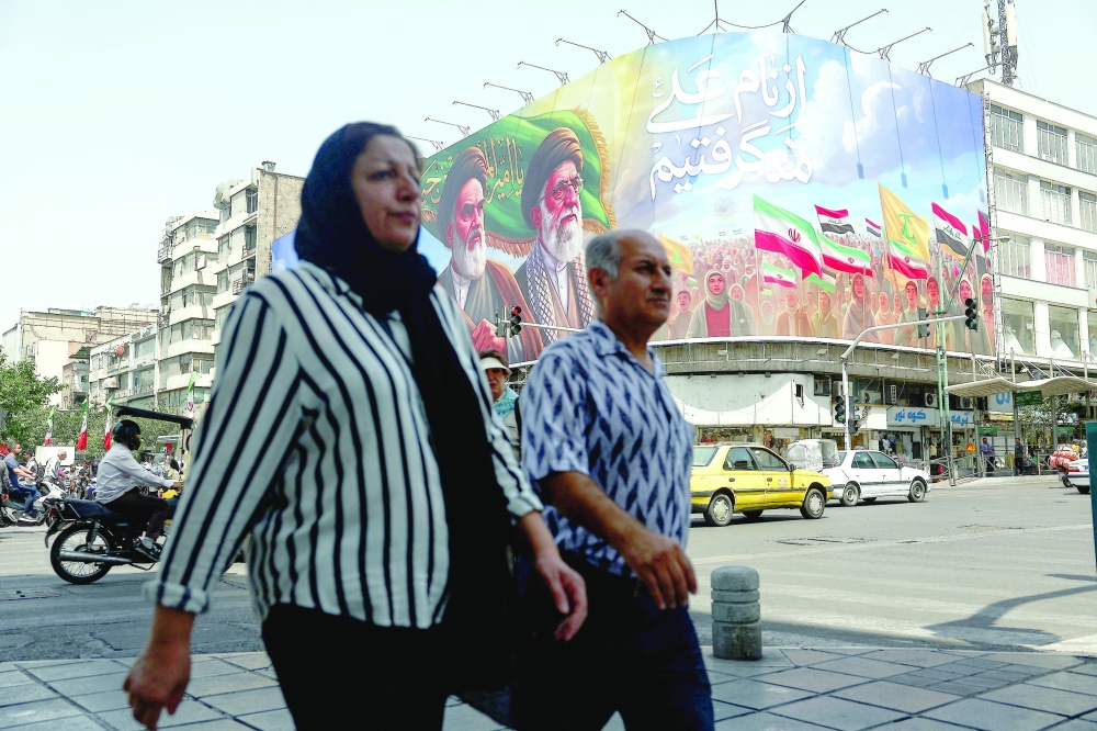 People walk past a billboard depicting the late leader of the Islamic Revolution, Ayatollah Ruhollah Khomeini, and the late Iran's Supreme Leader Ayatollah Ali Khamenei, on a street in Tehran. 
— Reuters