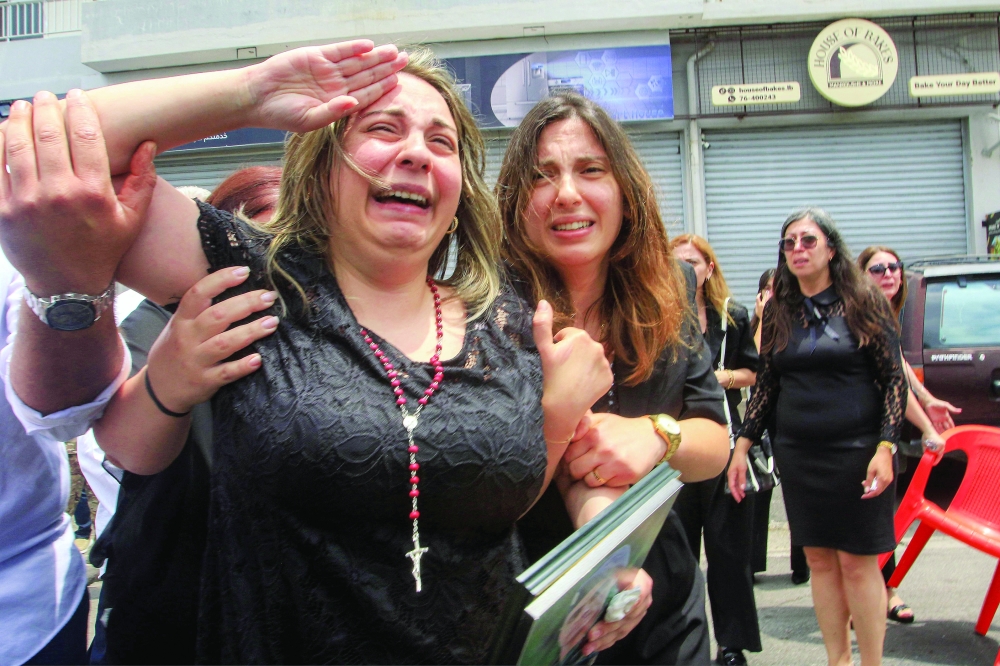 A woman salutes as mourners carry her husband's coffin past in the village of Kfar Jarra, southern Lebanon. — AFP