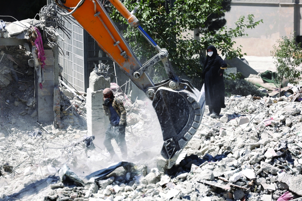 A woman stands among the rubble of her house, which was damaged in a strike, in Tehran, Iran. — Reuters 