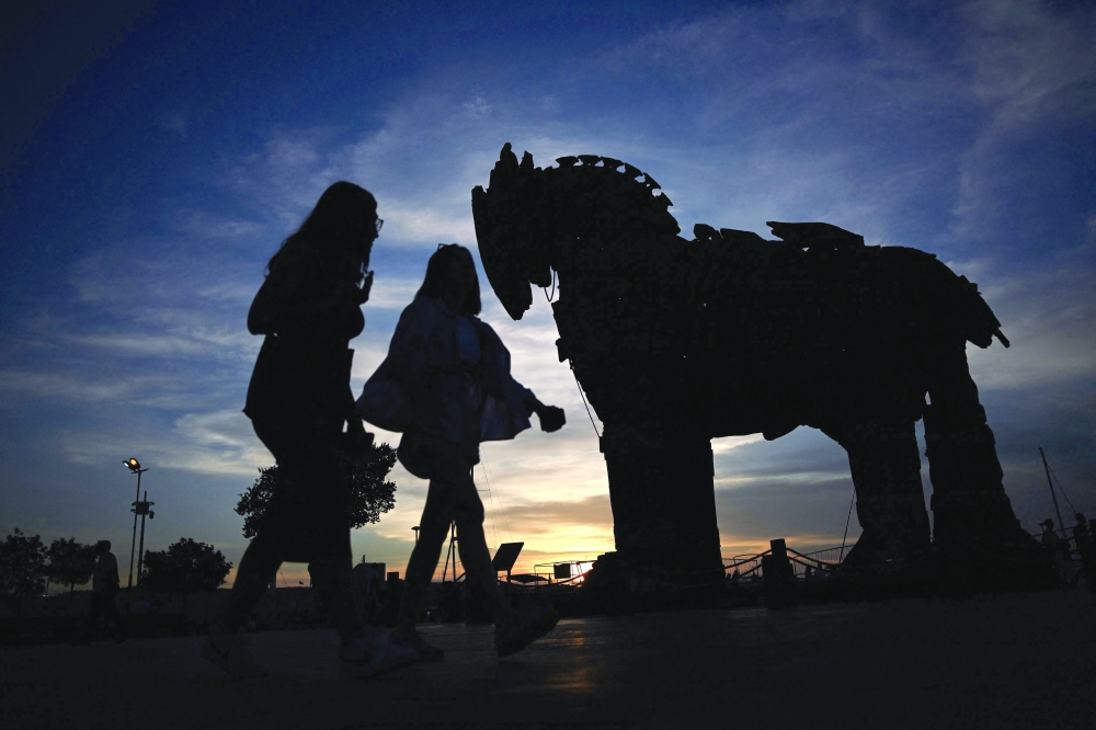 People walk at sunset in front of the Trojan Horse which was donated to be displayed at Çanakkale Square following the release of the movie 'Troy' in Çanakkale. — AFP