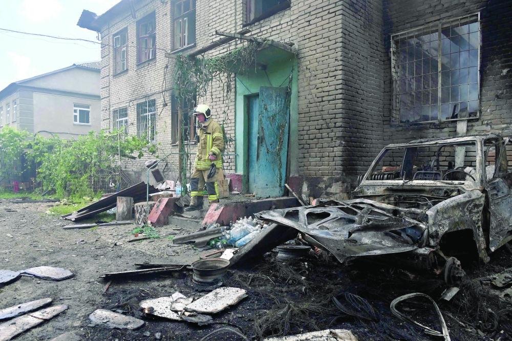 A Ukrainian rescuer stands on the porch of a damaged building following an air attack in Kharkiv. — AFP