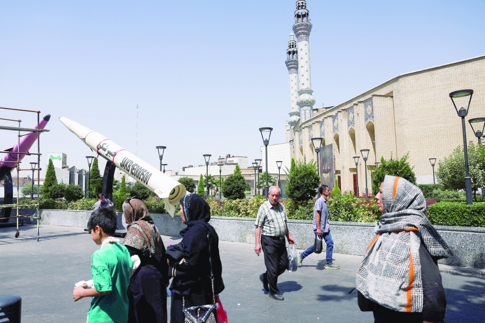 People walk next to a symbolic mock-up of an Iranian missile, on a street in Tehran. - Reuters