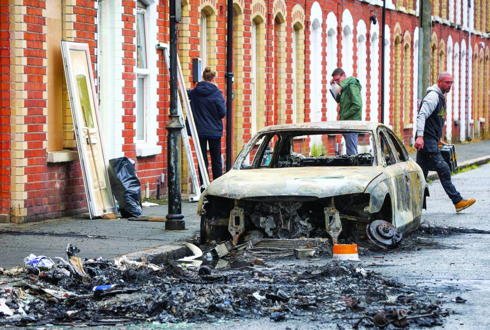 Tradespeople replace front doors of boarded-up houses off the Newtownards Road, in east Belfast, Northern Ireland. - AFP