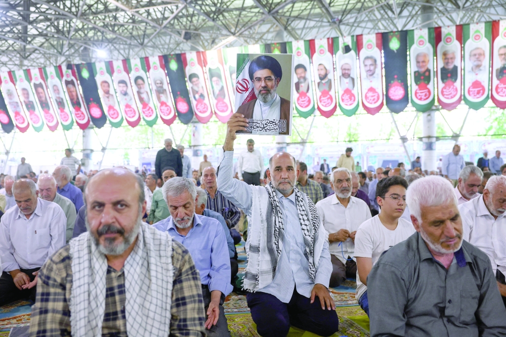 A man holds a picture of Iran's Supreme Leader, Mojtaba Khamenei, during Friday prayer in Tehran
