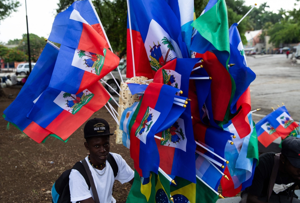 Picture shows a man selling the national flags of Haiti, Brazil and Argentina. — AFP