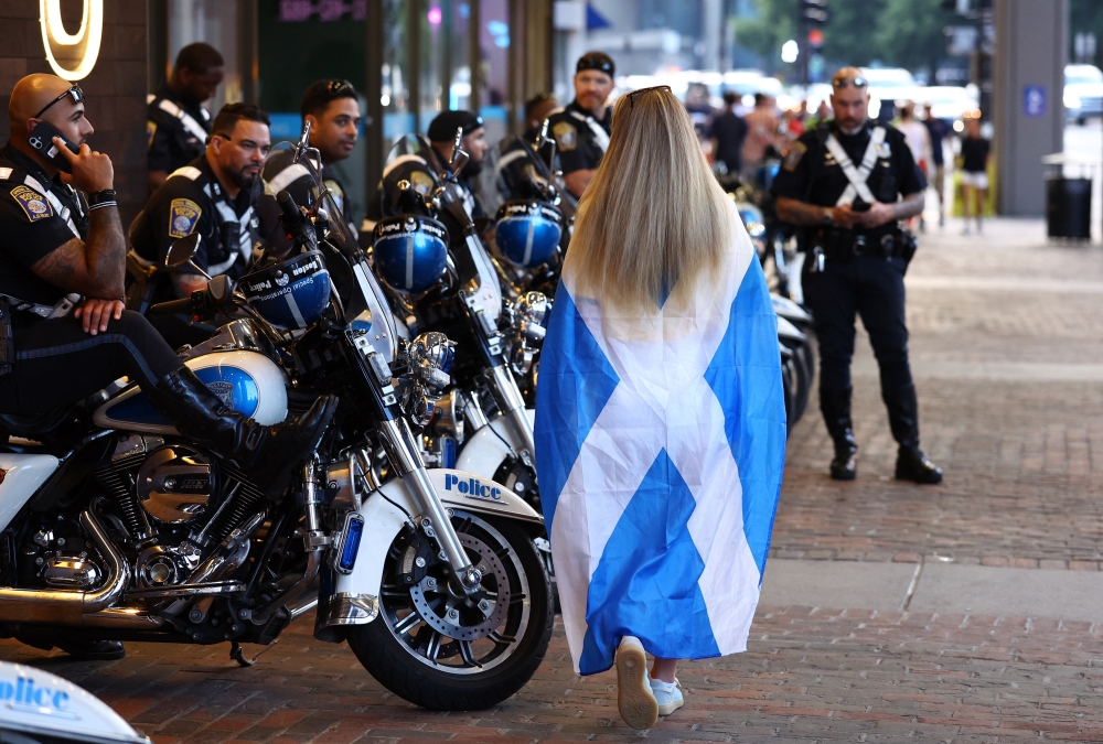  
A Scotland fan walks past police in Boston ahead of the match. — Reuters
