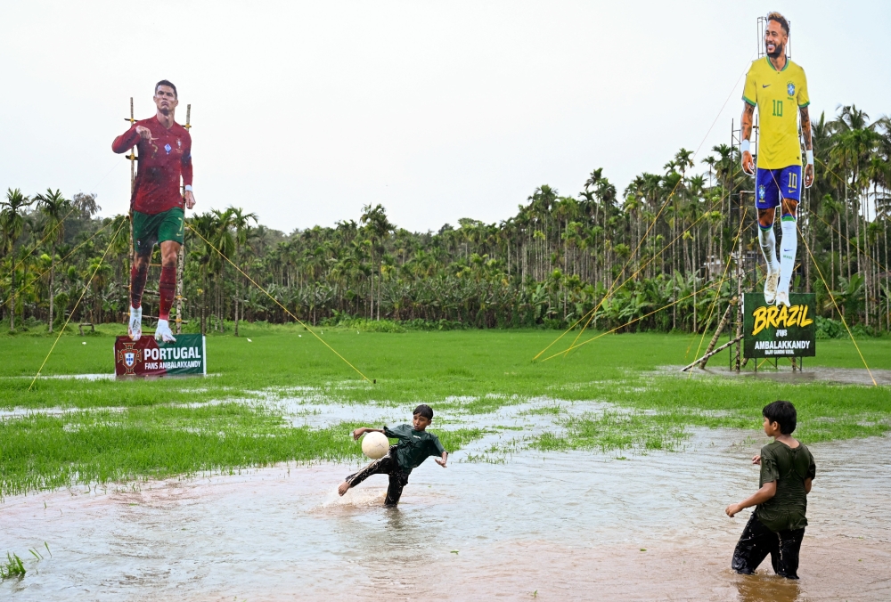 Children play soccer in front of cutouts of Portugal's Cristiano Ronaldo and Brazil's Neymar Jr. — Reuters