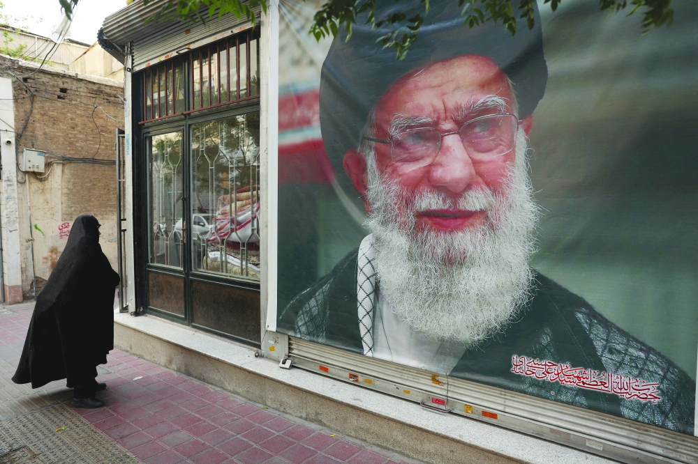 A woman walks past a banner with a picture of the late Iranian Supreme Leader Ayatollah Ali Khamenei, on a street in Tehran, Iran. — Reuters 