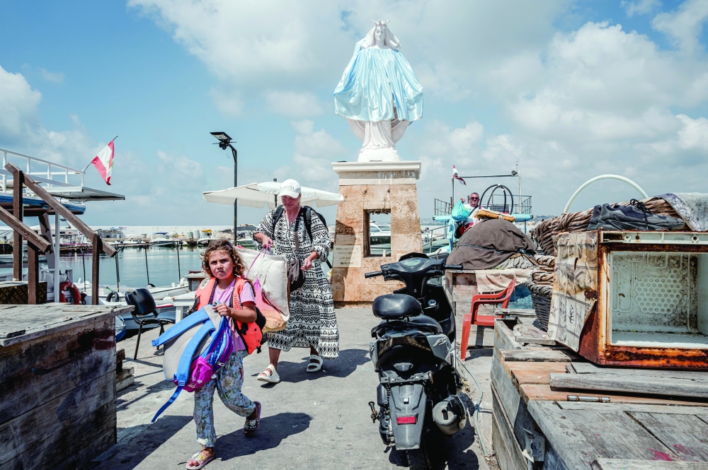 Local residents who had fled the fighting walk through the marina after disembarking, as they return to their homes in the nearby Christian Quarter in the southern port city of Tyre, Lebanon. — NYT
