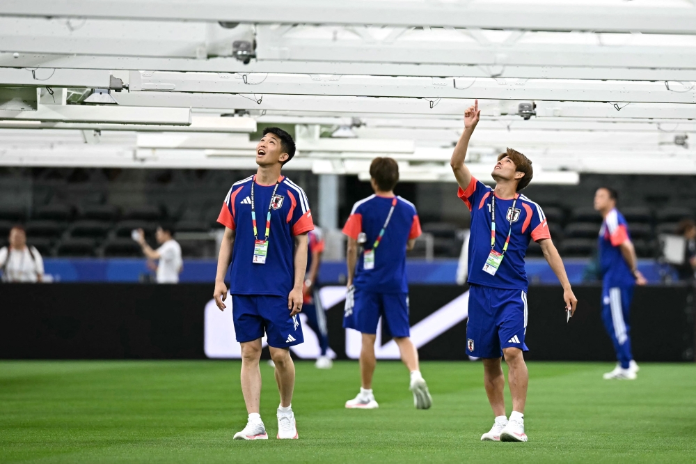 Japan's goalkeeper Tomoki Hayakawa (L) and midfielder Kaishu Sano (R) look at heat lamps. — AFP