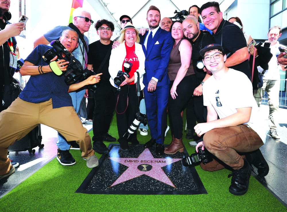 David Beckham poses with media members after unveiling his star on the Hollywood Walk of Fame, in Los Angeles, California. -Reuters