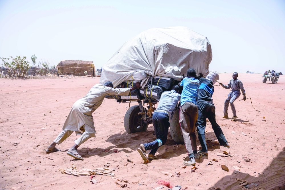 Men push a stuck cart toward Sudan at the Adre border. — AFP 
