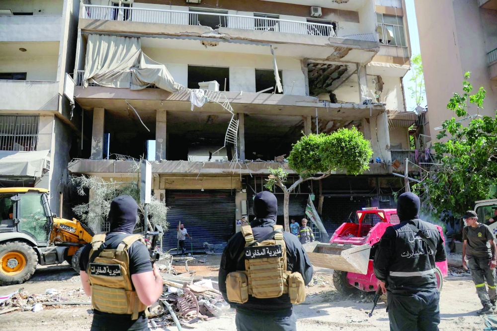 Lebanese army soldiers stand guard as people clear the rubble at the site of an Israeli airstrike that targeted a building in Beirut’s southern suburbs on Sunday. - AFP