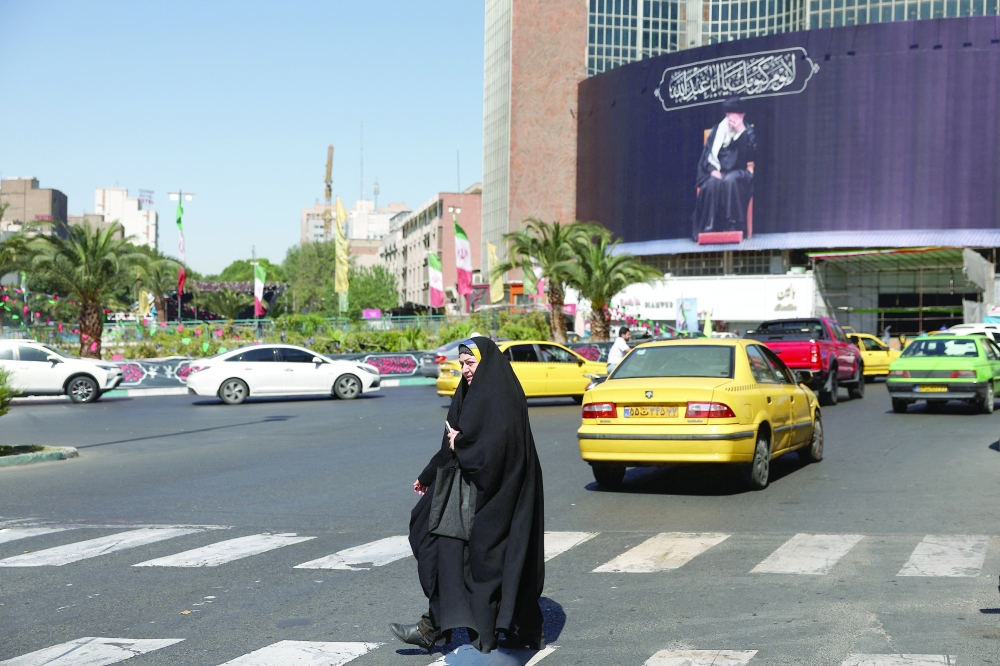 A woman walks past a billboard with a picture of the late Iran's Supreme Leader Ayatollah Ali Khamenei in Tehran, Iran. — Reuters 