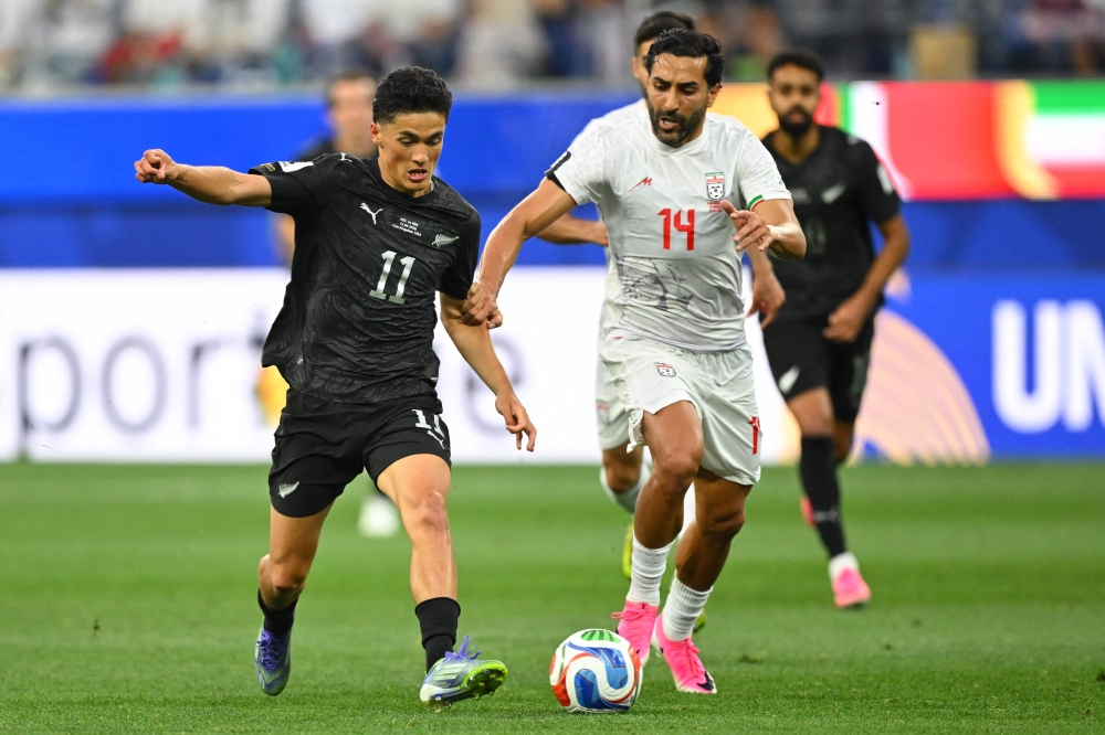 New Zealand's forward #11 Elijah Just and Iran's midfielder #14 Saman Ghoddos fight for the ball  