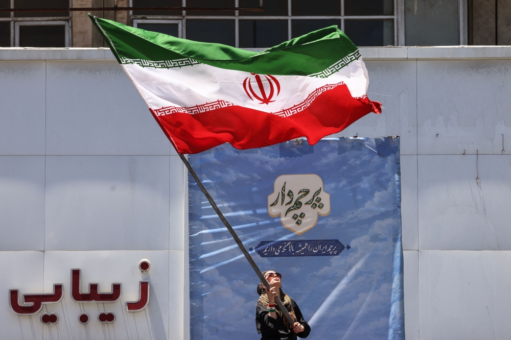 An Iranian woman waves a national flag at Valiasr Square in Tehran. — AFP