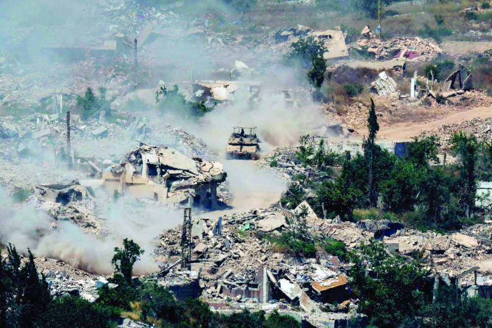 Israeli Merkava tanks drive along a road past destroyed buildings in southern Lebanon on Wednesday. — AFP