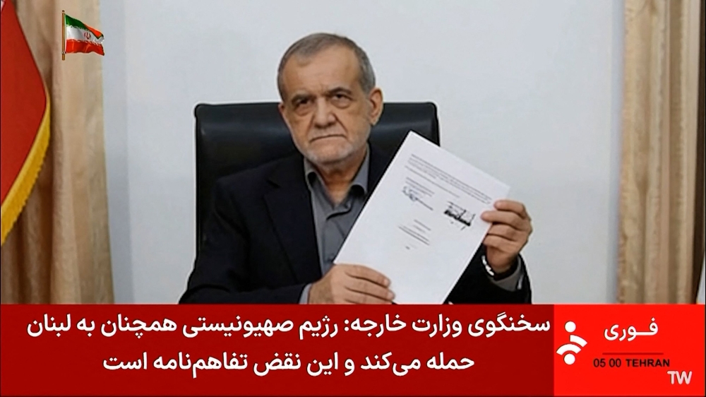 Iran's President Masoud Pezeshkian holding a document showing a memorandum of understanding he signed to end the Middle East war. US President Donald Trump and Iran's president signed a deal on June 17 meant to end the Middle East war